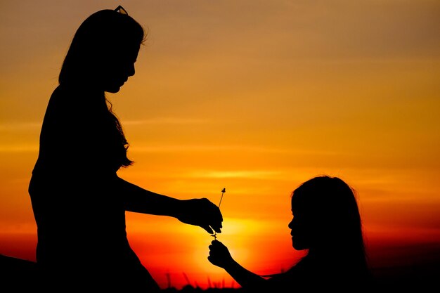 Photo silhouette d'une femme et d'un enfant au coucher du soleil