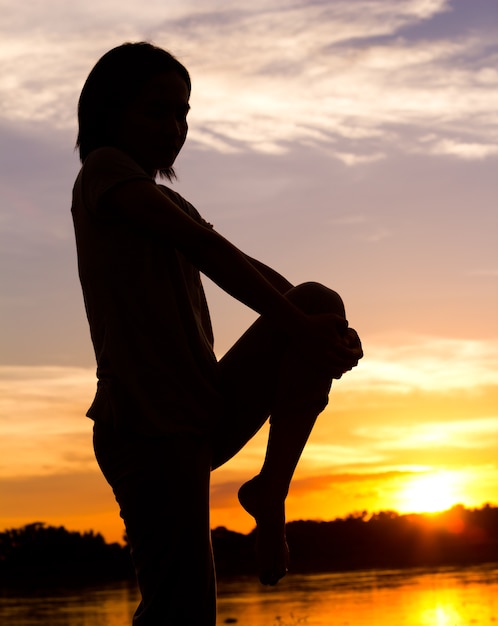 Silhouette de femme exerçant sur le magnifique fond de coucher de soleil.