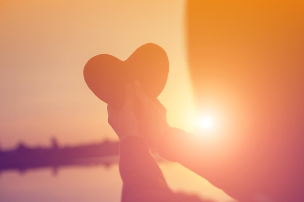 Photo silhouette d'une femme en forme de cœur contre un ciel orange