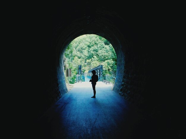 Photo silhouette d'une femme marchant dans un tunnel