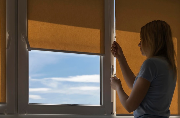 Silhouette d'une femme ouvrant les stores un matin ensoleillé