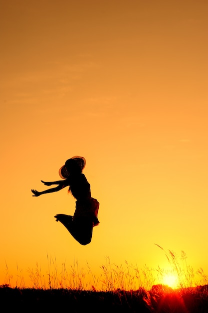 Silhouette de femme sautant au coucher du soleil