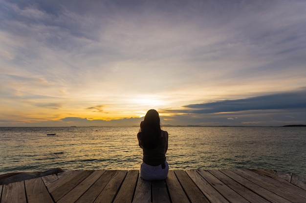 Silhouette de femme sautant sur la mer au coucher du soleil flou et discret