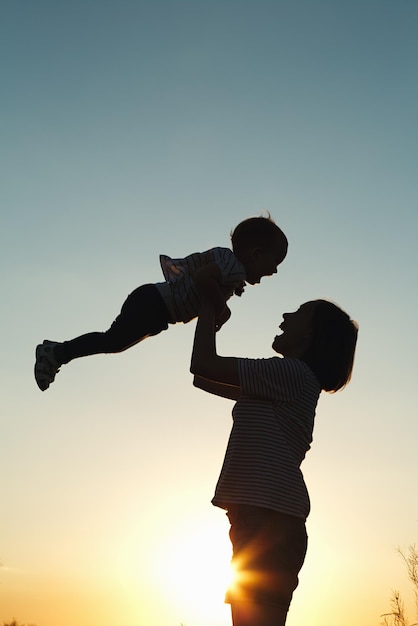 Silhouette d'une femme avec son enfant au coucher du soleil