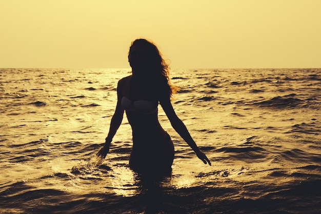 Silhouette d&#39;une femme svelte dans l&#39;eau à la plage au soleil