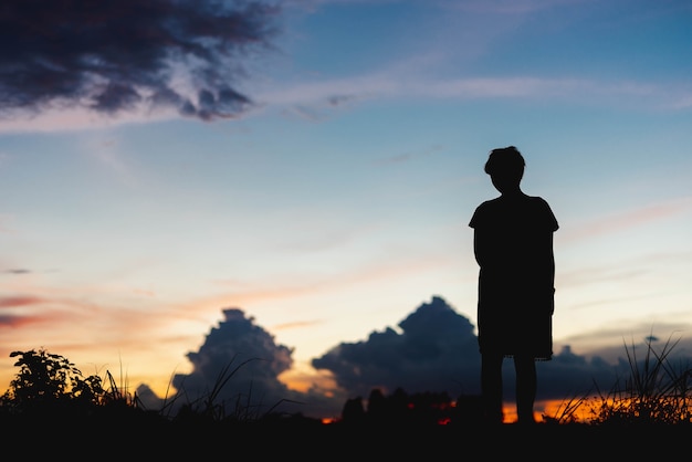 Silhouette femme triste debout au coucher du soleil