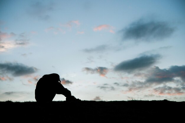 Photo silhouette d'une femme triste à genoux au coucher du soleil