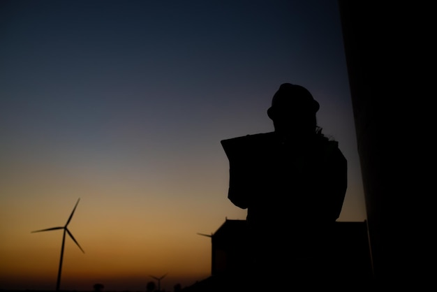 Silhouette de femmes ingénieures travaillant et tenant le rapport à la centrale éolienne Power Generator Station sur mountainThailand people