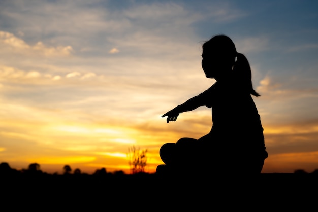 Photo silhouette de femmes tristes et déprimées assises et pointant vers l'allée du parc avec coucher de soleil