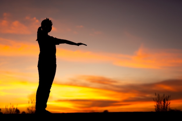 Photo silhouette de femmes tristes et déprimées assises et pointant vers l'allée du parc avec coucher de soleil