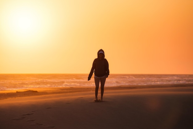 Silhouette d'une fille dans le désert Dunes de sable et bord de mer pendant le coucher du soleil Paysage d'été