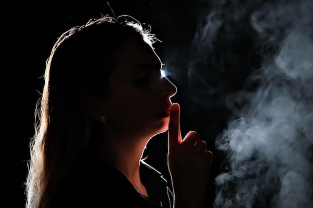 Silhouette d'une fille dans la fumée noire fille à vapeur dans une pièce sombre