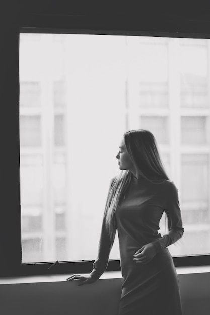 Silhouette d'une fille devant une fenêtre photographie en noir et blanc