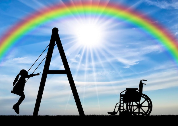 Silhouette d'une fille handicapée sur une balançoire à côté d'un fauteuil roulant sur fond de ciel avec un arc-en-ciel. Concept de jouer aux enfants handicapés