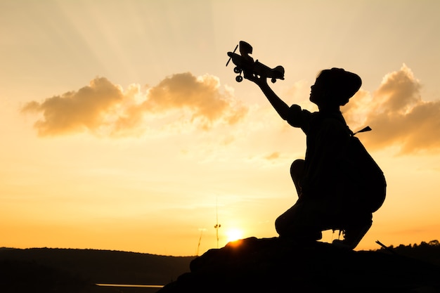 Photo silhouette de fille jouant de l'avion en bois dans la nature