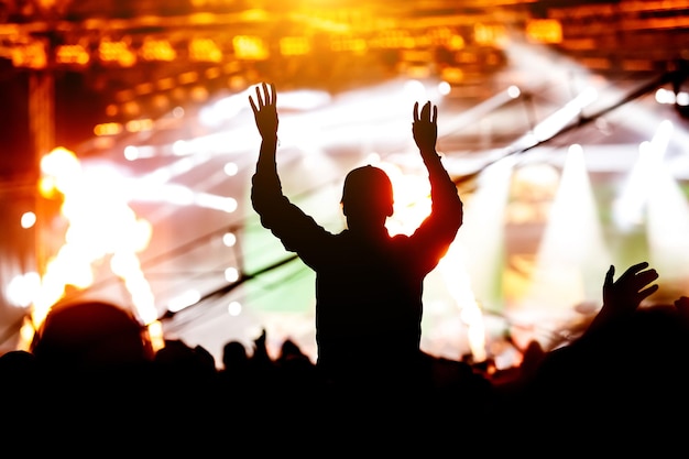 Silhouette de fille avec les mains levées sur le concert de musique.