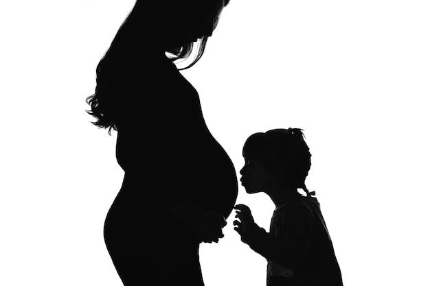 Photo la silhouette de la fille qui embrasse la mère enceinte