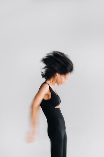 Une silhouette floue d'une femme en tenue de sport noire est engagée dans une méditation kali dynamique dans la salle de yoga