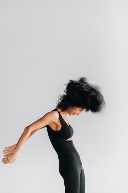 Une silhouette floue d'une femme en tenue de sport noire est engagée dans une méditation kali dynamique dans la salle de yoga