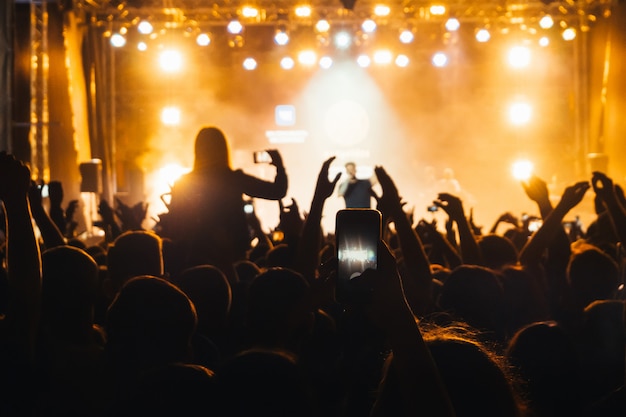 La silhouette de la foule du public au concert de Basta et une main avec un téléphone portable