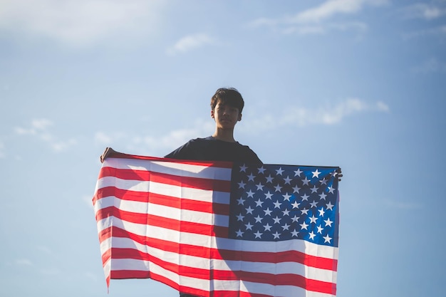 Silhouette de garçon tenant le drapeau des États-Unis, l'homme tient en agitant le drapeau américain des États-Unis