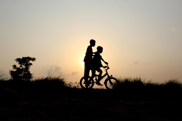 Silhouette de garçons à vélo contre le ciel au coucher du soleil