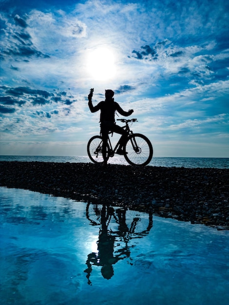 Silhouette d'un gars sur un vélo de montagne sur fond de mer et de belles textures de nuages