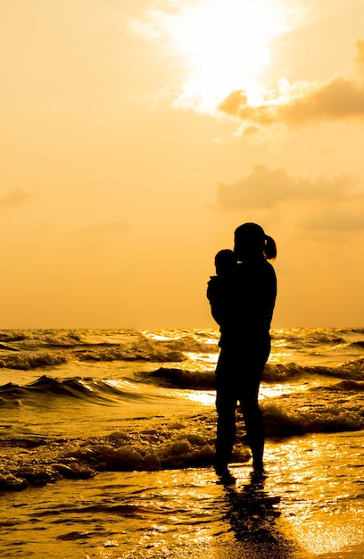 Silhouette avec des gens debout sur la plage avec fond de coucher de soleil