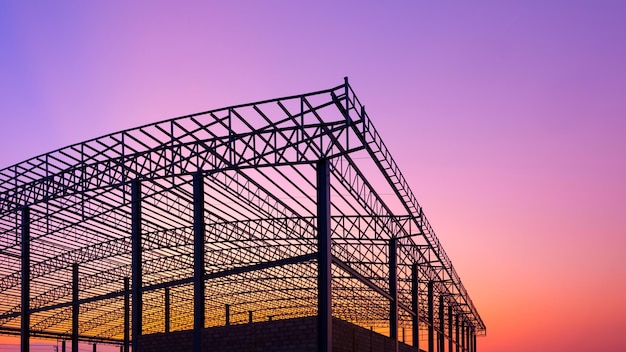 Silhouette d'une grande structure d'usine sur le chantier de construction contre un ciel de crépuscule coloré