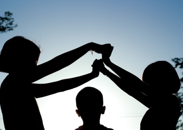 Silhouette, groupe d&#39;enfants heureux, jouant sur fond de coucher de soleil.