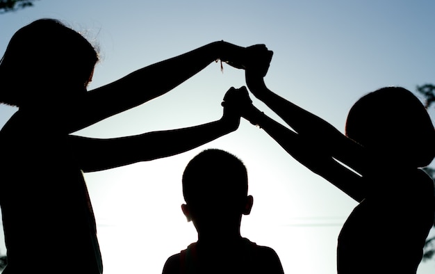 Silhouette, groupe d&#39;enfants heureux, jouant sur fond de coucher de soleil.