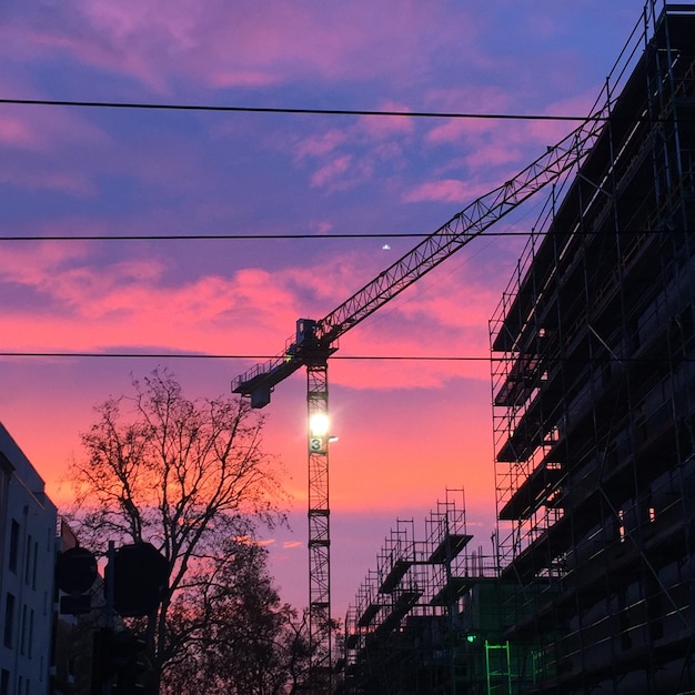 Photo la silhouette d'une grue sur le chantier au coucher du soleil