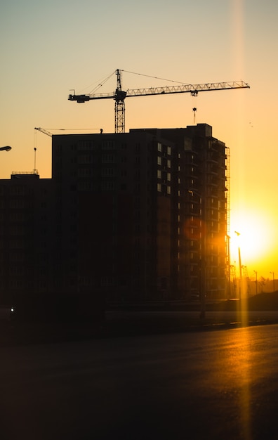 Photo silhouette de grues de construction sur de nouveaux bâtiments résidentiels au coucher du soleil. contexte urbain.