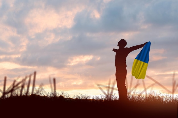 Silhouette d'un homme d'affaires tenant le drapeau ukrainien avec fond de lever de soleil