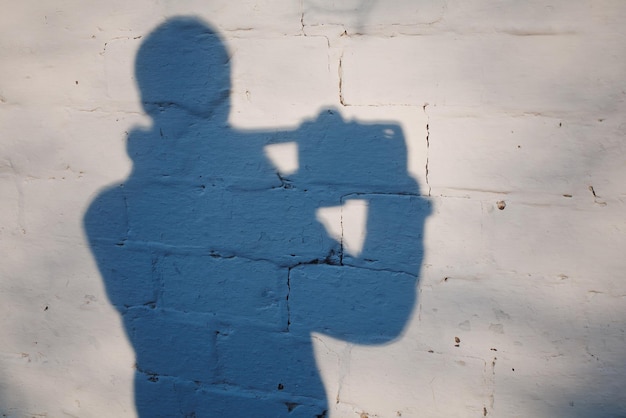 silhouette d'un homme avec un appareil photo sur un fond de mur blanc