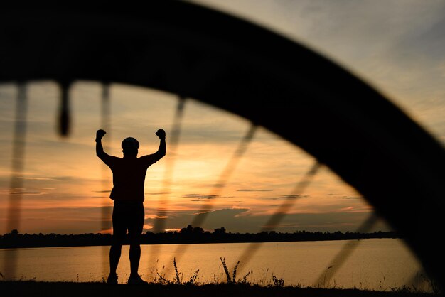 Silhouette d'homme asiatique faire du vélo au coucher du soleil