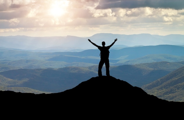 Silhouette d'un homme au sommet d'une montagne. Personne sur le rocher. Concept de sport et de vie active