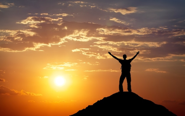 Silhouette d'un homme au sommet d'une montagne. Silhouette de personne sur le rocher. Concept de sport et de vie active