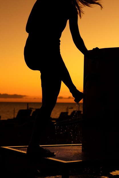 Photo silhouette d'homme contre la mer au coucher du soleil