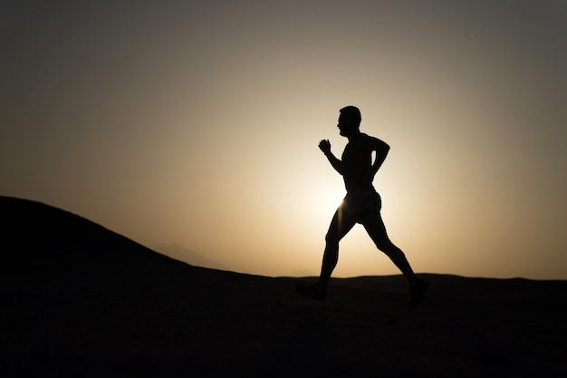 Silhouette d'homme en cours d'exécution au ciel coucher de soleil