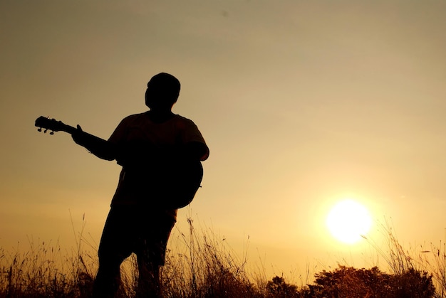 Silhouette d'un homme debout sur un champ contre le ciel au coucher du soleil