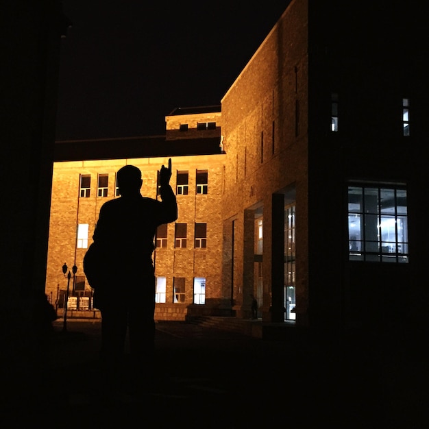 Photo silhouette d'un homme debout dans une ville éclairée la nuit