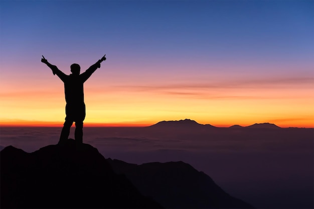 Silhouette d'un homme debout sur une montagne contre le ciel au coucher du soleil