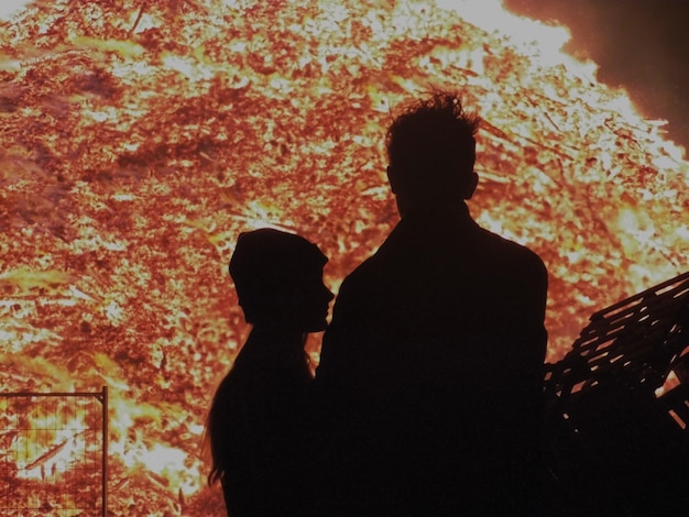 Photo silhouette d'un homme et d'une femme debout contre le feu la nuit.