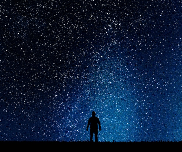 Silhouette d'homme sur fond d'étoiles. L'homme désire deviner en regardant les étoiles.