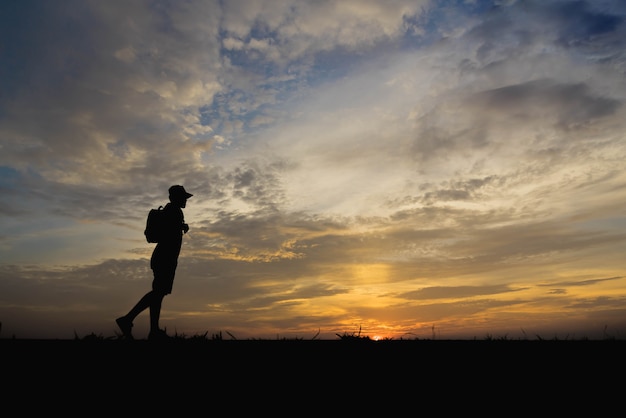 Silhouette d'un homme heureux de marcher au coucher du soleil.