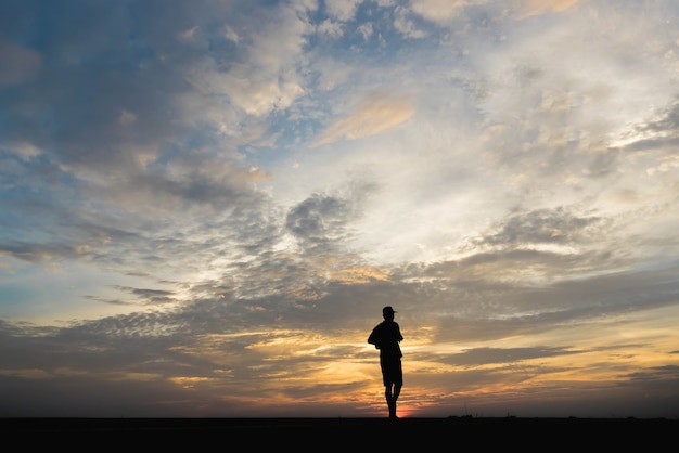 Silhouette d'un homme heureux de marcher au coucher du soleil.