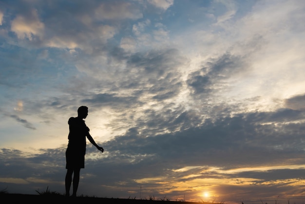 Silhouette d'un homme avec un homme exerçant au coucher du soleil.