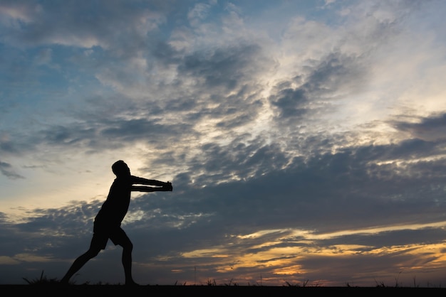 Silhouette d'un homme avec un homme exerçant au coucher du soleil.