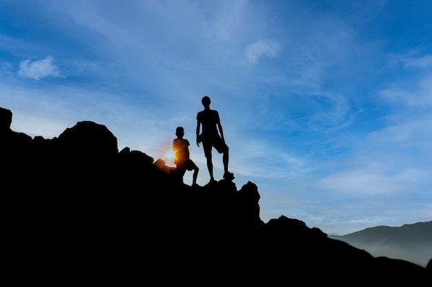 Silhouette d'un homme et d'un homme sur une montagne et un ciel bleu